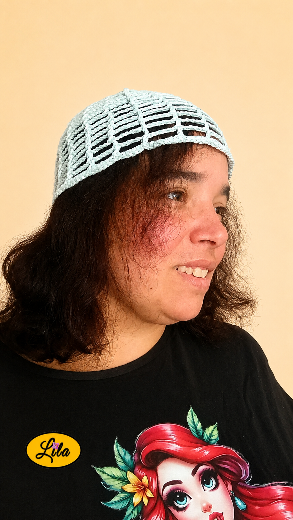 Bonnet d'été en crochet ajouré vert menthe porté par un mannequin de profil droit avec les cheveux lâchés et le regard tourné vers la droite mettant en valeur son style bohème, sa légèreté et son crochet fait main