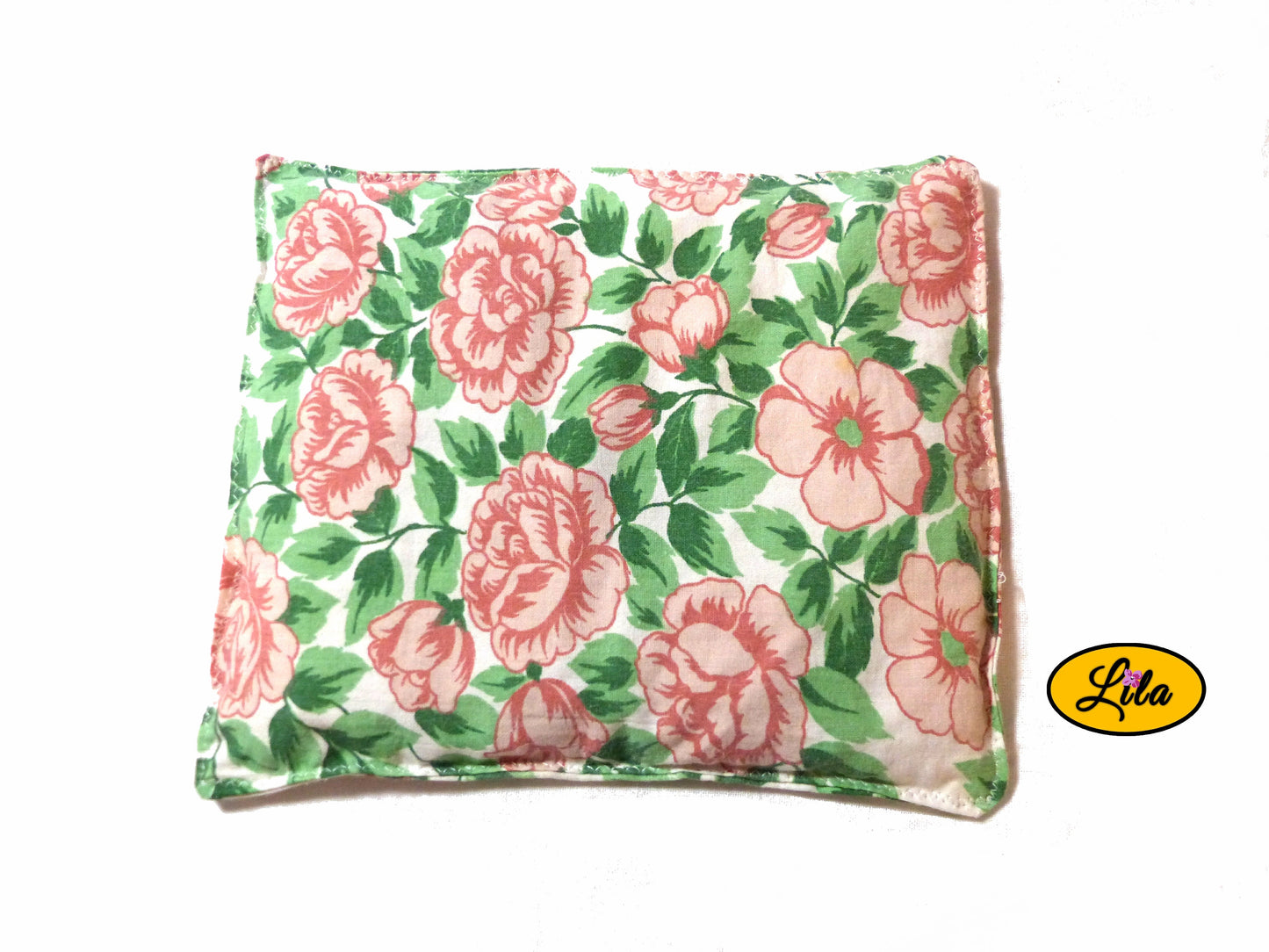 Bouillotte carrée fleurie réalisée dans un ancien drap de lit recyclé remplie de noyaux de cerise tournée légèrement d’un quart de tour vue de haut sur fond blanc style artisanal et chaleureux