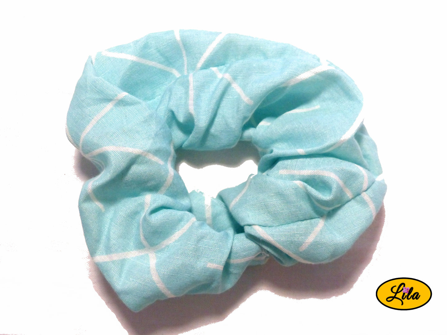 Chouchou pour cheveux en tissu bleu clair avec motifs de lignes blanches asymétriques présenté sur fond blanc style moderne et artisanal