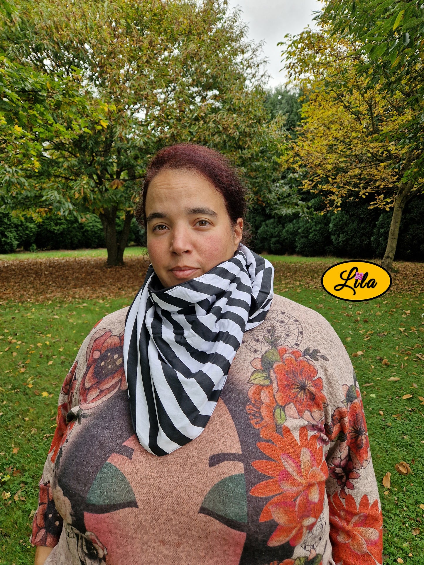 Foulard triangulaire à lignes noir et blanc porté fermé par une jeune femme dans un parc automnal avec nœud caché sous la pointe du foulard style graphique et élégant