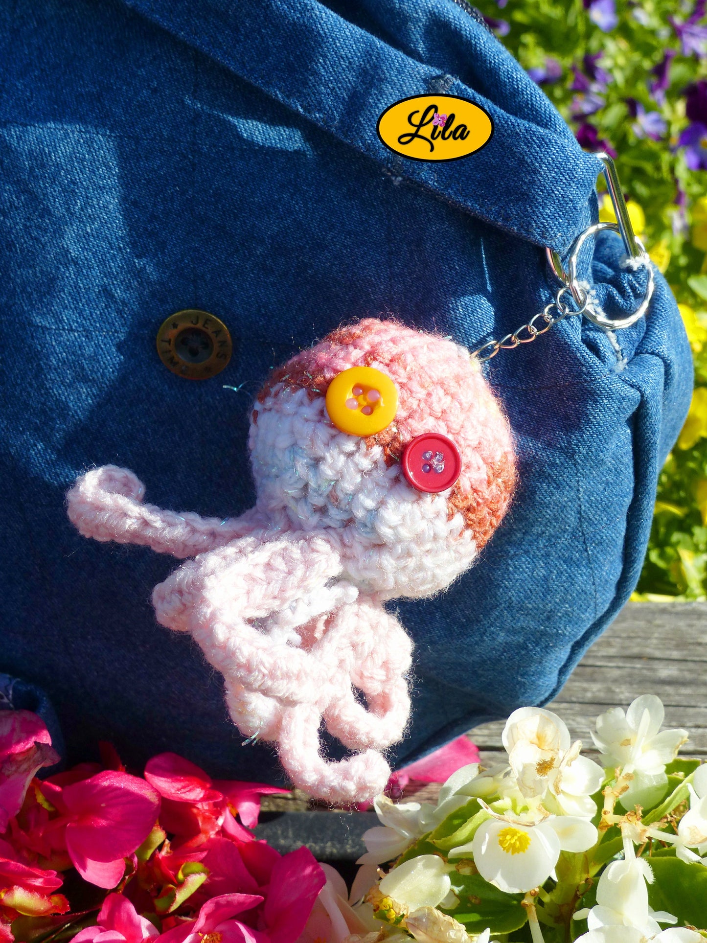 Porte-clé Poulpy pieuvre amigurumi rose aux dégradés pailletés réalisée au crochet avec yeux en boutons orange et fuchsia accroché à un sac style bohème et artisanal
