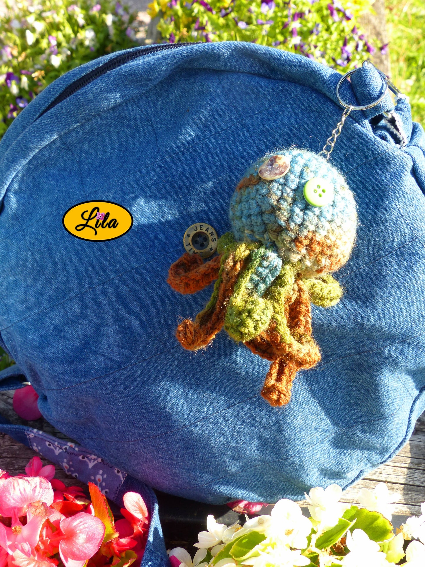 Porte-clé Poulpy pieuvre amigurumi chamarrée aux tons vert bleu et brun réalisée au crochet avec yeux en boutons vert et multicolore accroché à un sac style bohème et artisanal