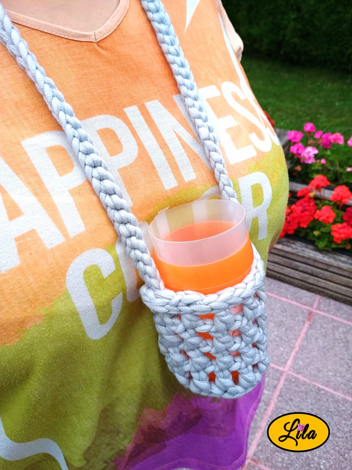 Porte-gobelet gris porté autour du cou façon collier par un mannequin vu de profil droit en extérieur avec gobelet à l’intérieur style festival et artisanal