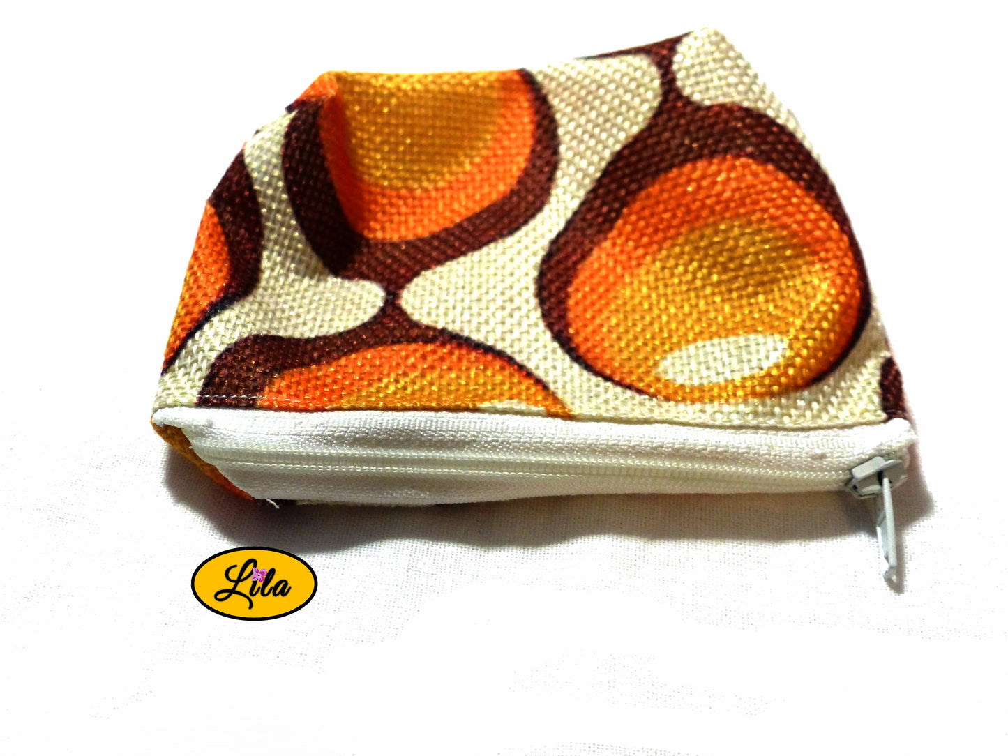 Porte-monnaie en tissu vintage à motifs ronds orange avec fermeture éclair blanche posé de face avec fermeture visible sur fond blanc style graphique et pratique