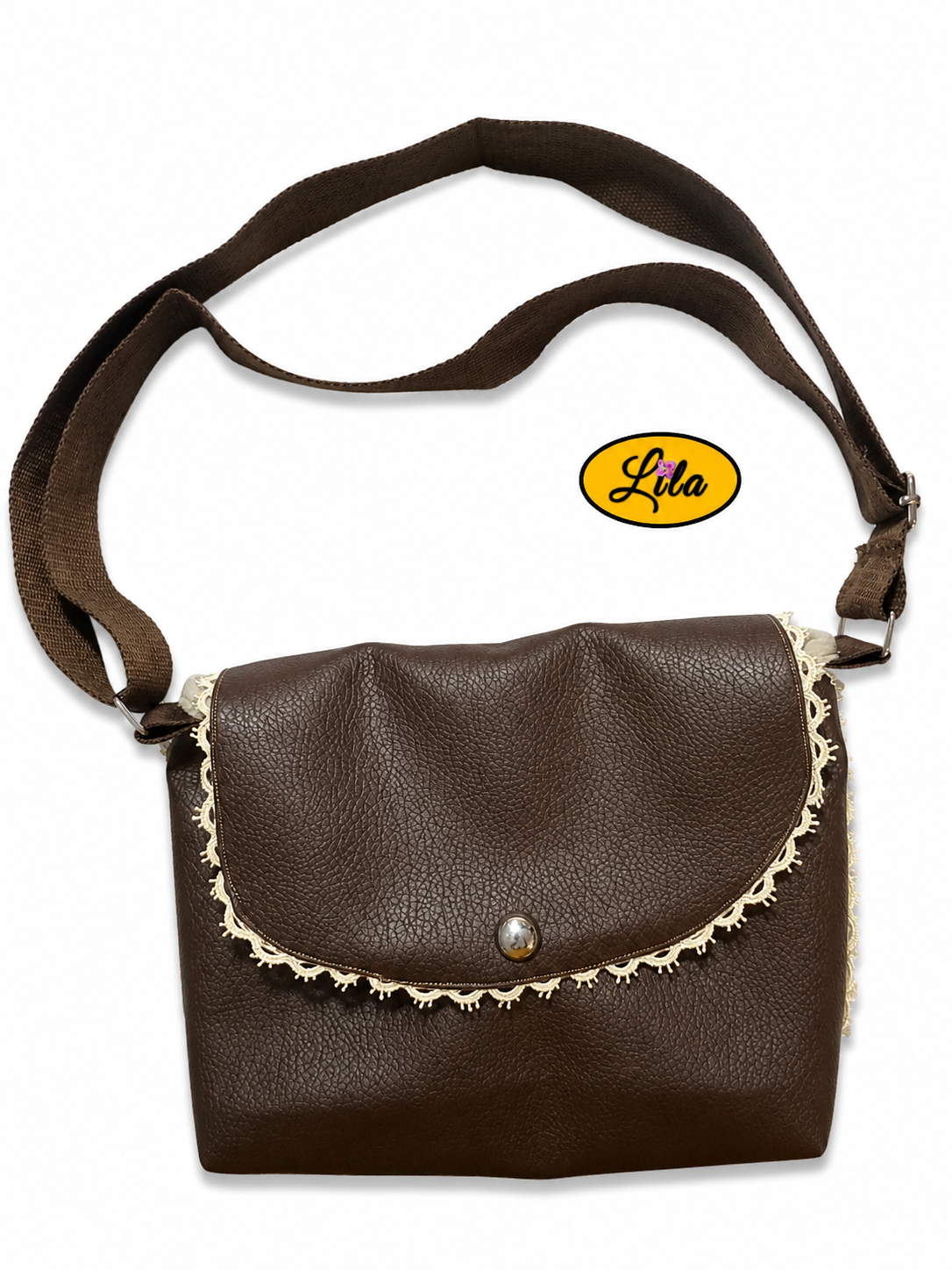Sac bandoulière en simili cuir brun vu de haut sur fond blanc avec sangle en coton brun posée sur le dessus, fermeture à pression argentée et rivet décoratif, création artisanale élégante