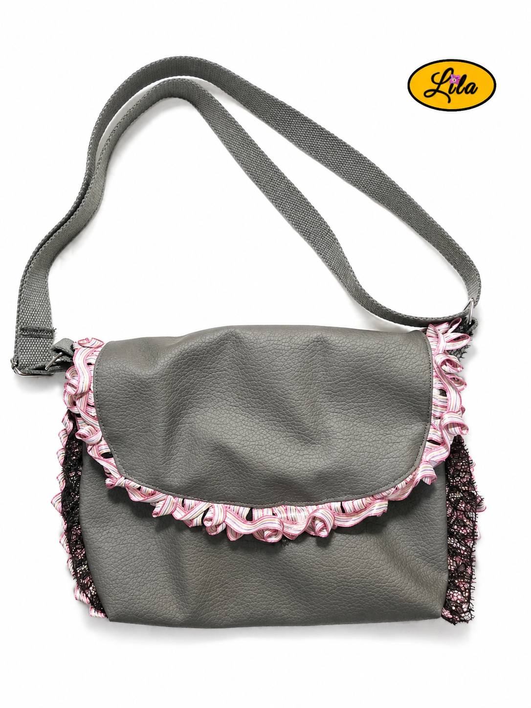 Sac bandoulière en simili cuir gris vu de haut sur fond blanc avec sangle en coton gris posée sur le dessus, bordure plissée aux nuances de rose, galon noir et fermeture à pression argentée, création artisanale