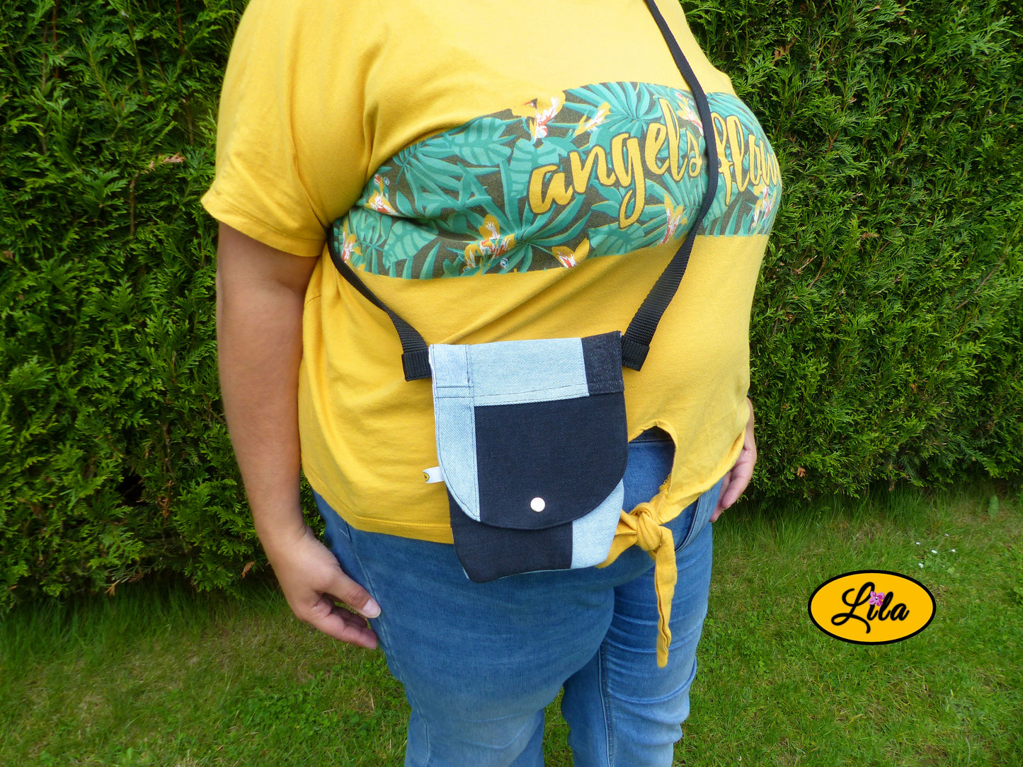 Sac bandoulière pour téléphone en patchwork de jeans recyclés bleu clair et noir porté par une jeune femme devant une haie dans un jardin avec photo cadrée sur le sac mettant en valeur son format compact et son style upcyclé