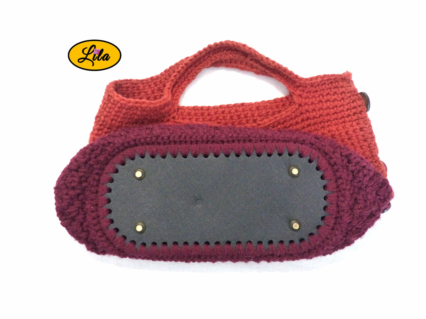Sac à main au crochet rouille et pourpre couché sur fond blanc avec vue sur le fond en simili cuir noir détail finition et maintien
