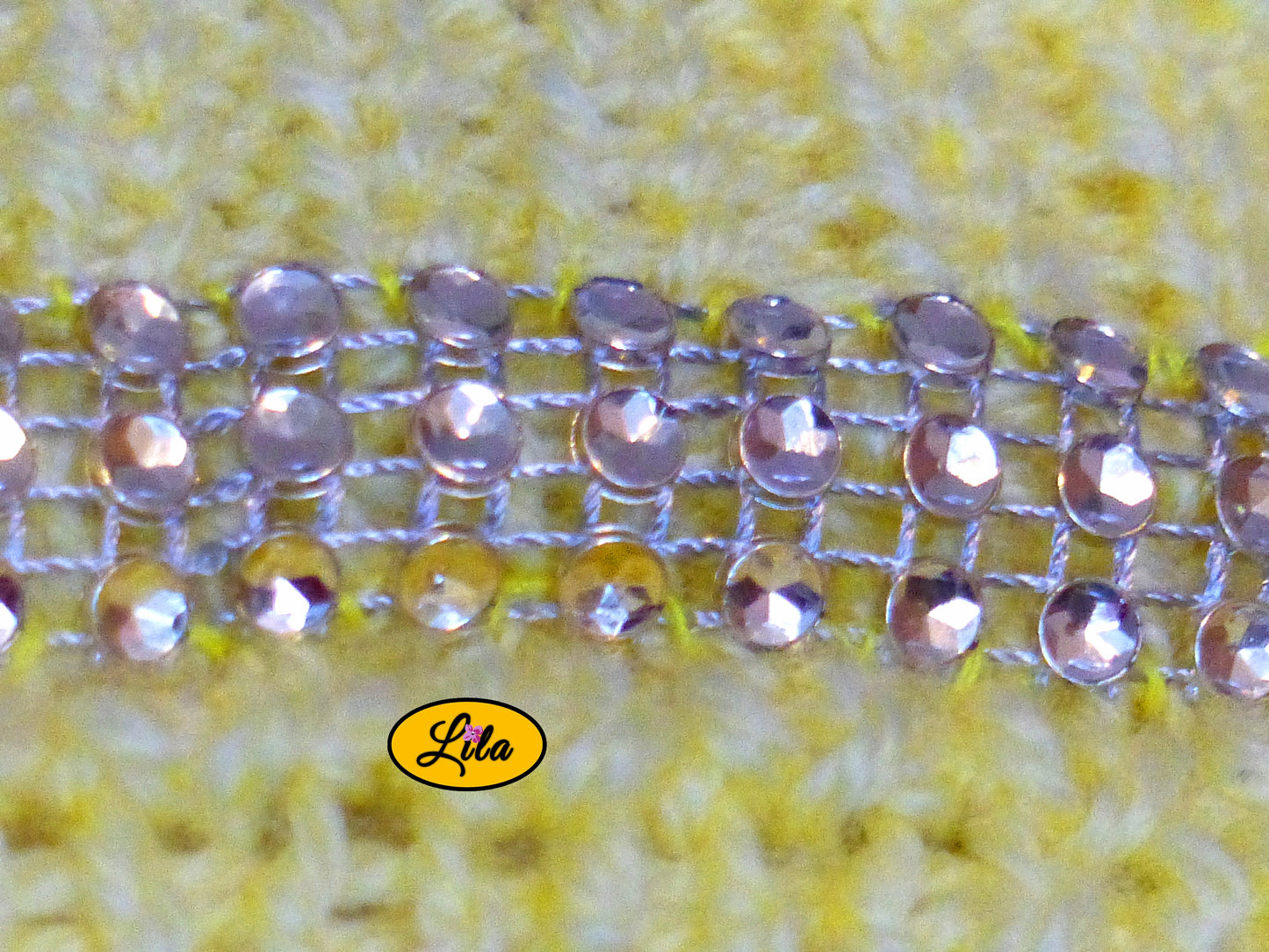 Zoom sur la bande de strass cousue au niveau de la poitrine du top Augustine jaune tricoté à la main détail brillant et élégant