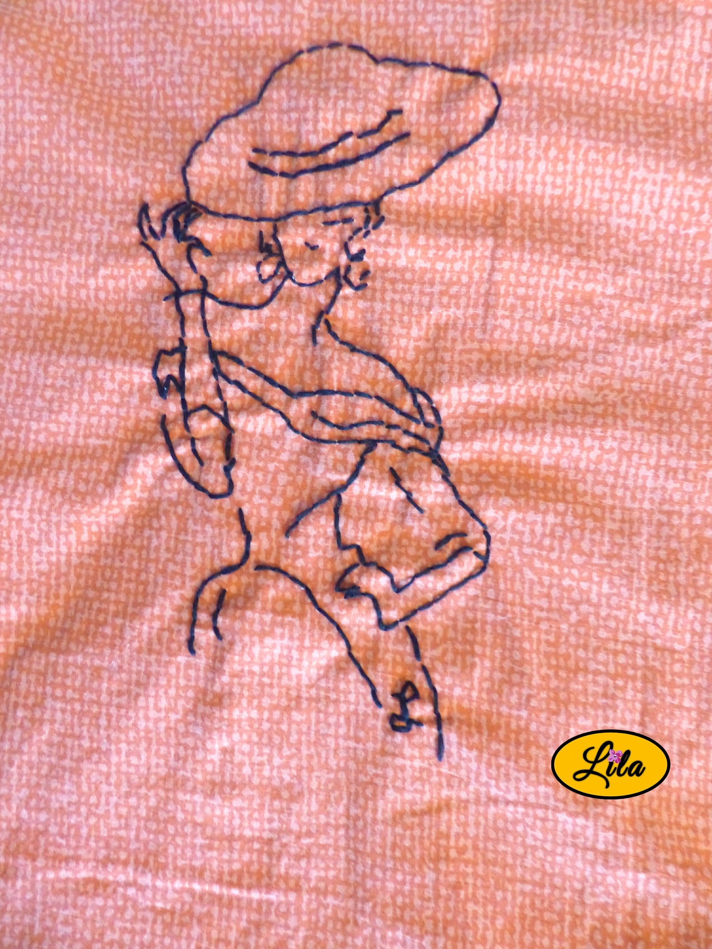 Zoom sur la broderie artisanale représentant une mannequin vintage réalisée sur un tote bag orangé mettant en valeur les détails de la broderie et les finitions faites main