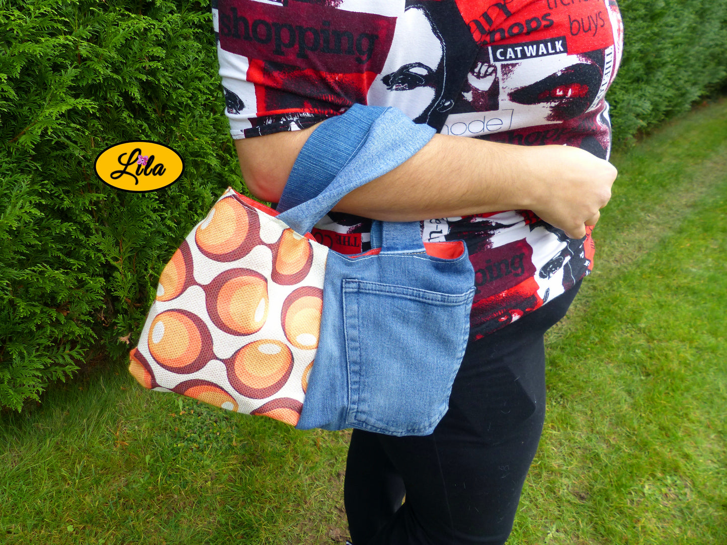 Sac à main en jeans et ancienne nappe vintage à ronds orange porté dans le creux du bras en extérieur photo cadrée sur le sac style rétro et artisanal