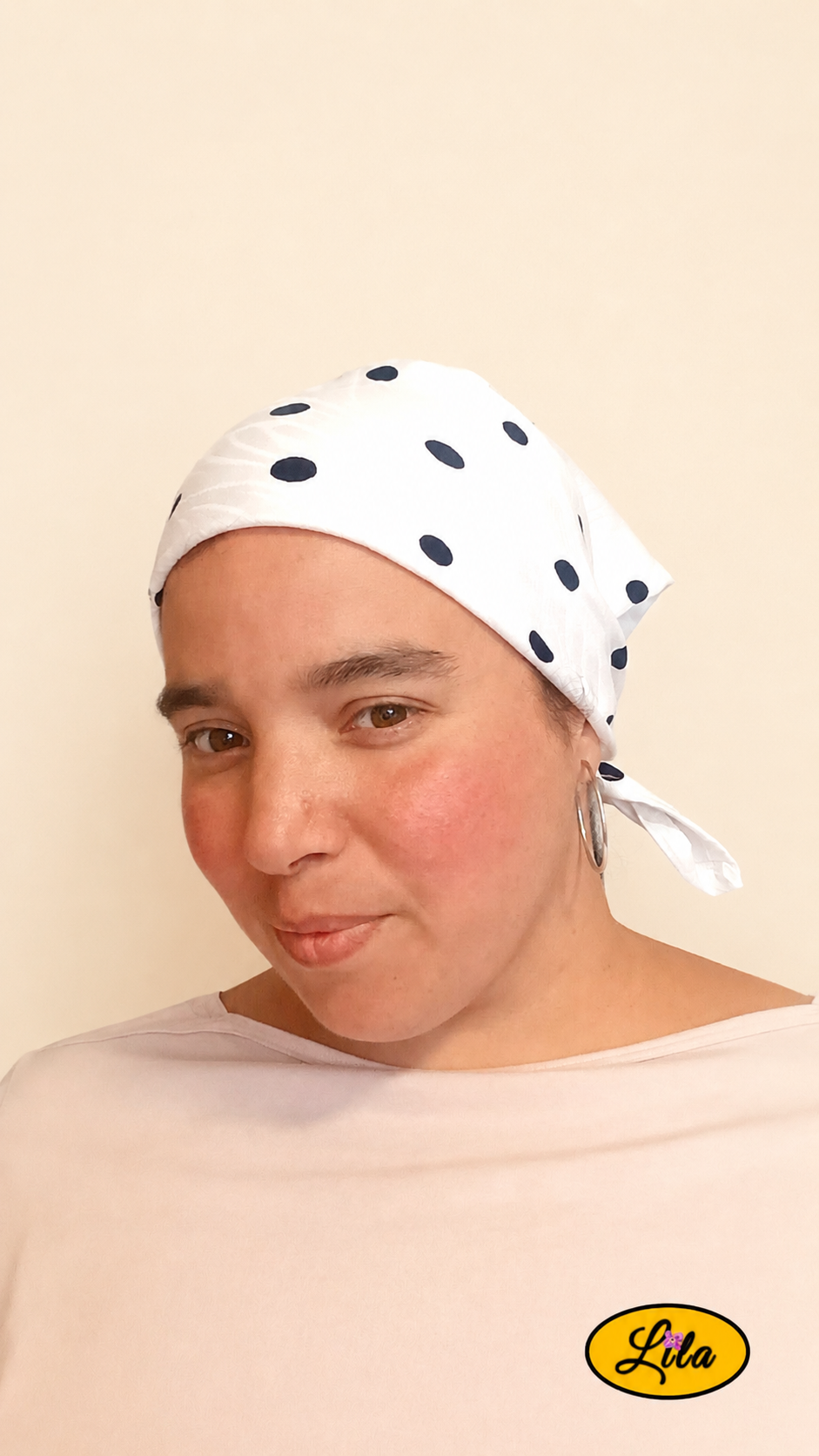 Bandana blanc à pois marine porté dans les cheveux par une femme de profil droit aux cheveux attachés style rétro et élégant