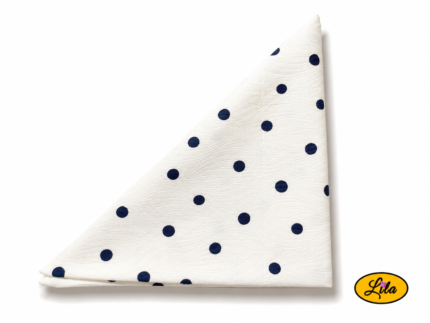 Bandana blanc à pois marine plié en triangle vu de haut sur fond clair mettant en valeur le motif à pois et les finitions du tissu