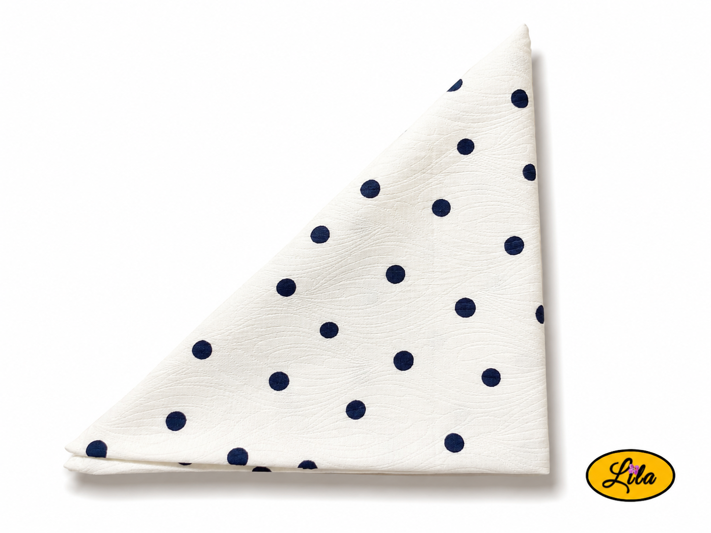 Bandana blanc à pois marine plié en triangle vu de haut sur fond clair mettant en valeur le motif à pois et les finitions du tissu