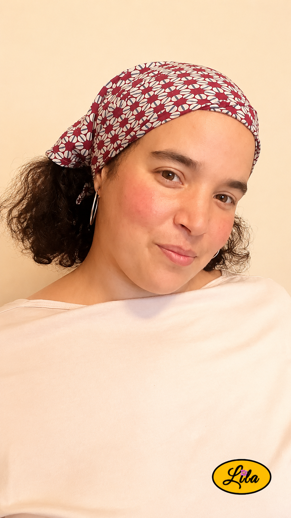 Bandana bordeaux à motifs géométriques vintage porté dans les cheveux par une femme de profil droit avec les cheveux lâchés sous le bandana style graphique et artisanal