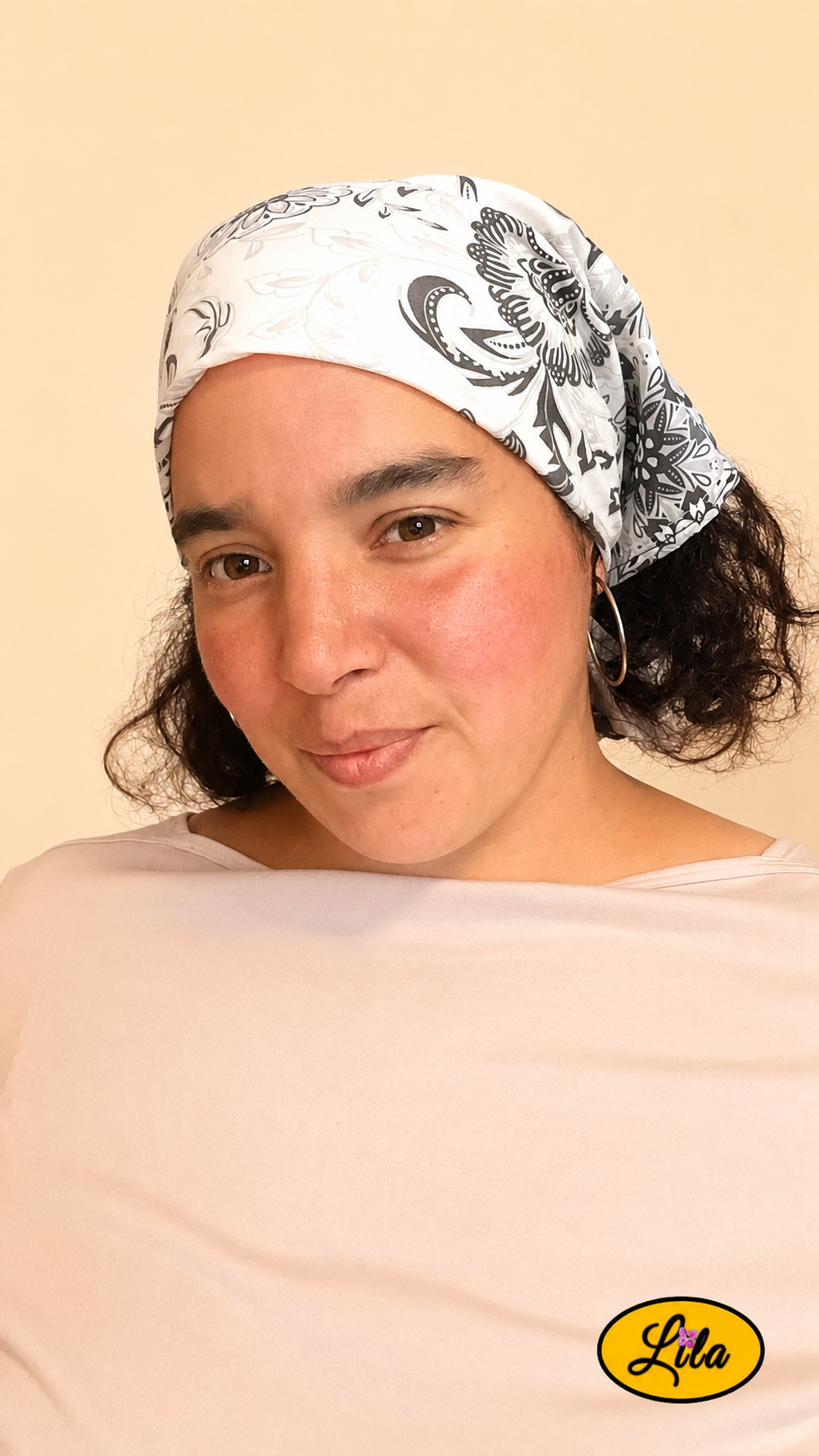 Bandana noir et blanc à motifs baroques porté dans les cheveux par une jeune femme légèrement de profil gauche avec les cheveux lâchés et un léger sourire style rétro et féminin