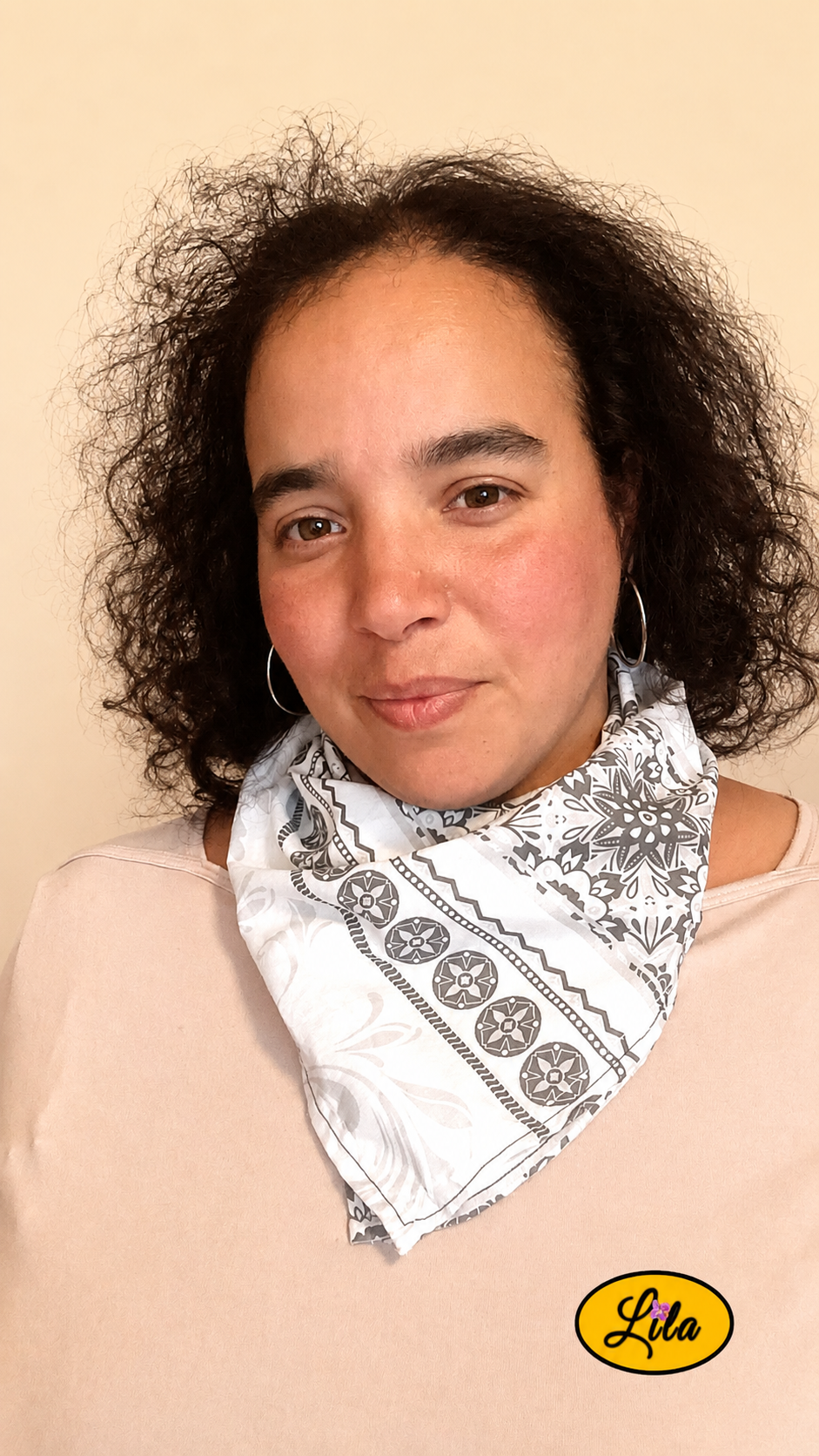Bandana noir et blanc à motifs baroques porté autour du cou par une jeune femme de face aux cheveux lâchés style élégant et tendance