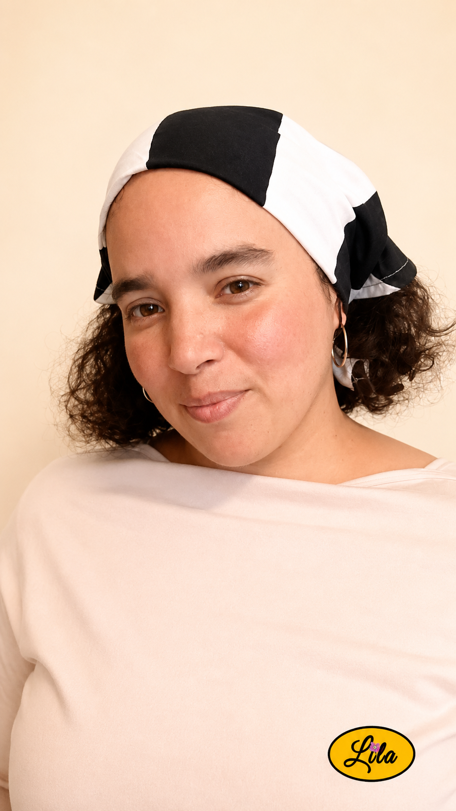 Bandana noir à larges rayures blanches porté dans les cheveux par une femme de profil gauche avec les cheveux lâchés sous le bandana style graphique et tendance