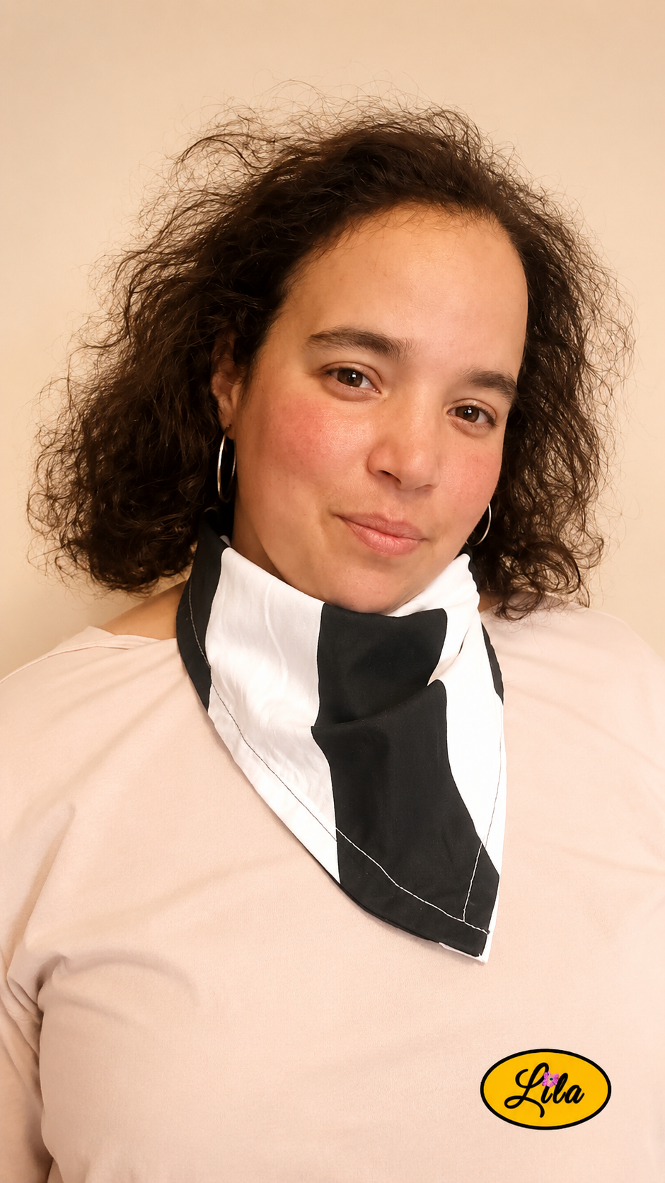 Bandana noir à larges rayures blanches porté autour du cou par une femme aux cheveux lâchés de face légèrement de profil droit style élégant et moderne