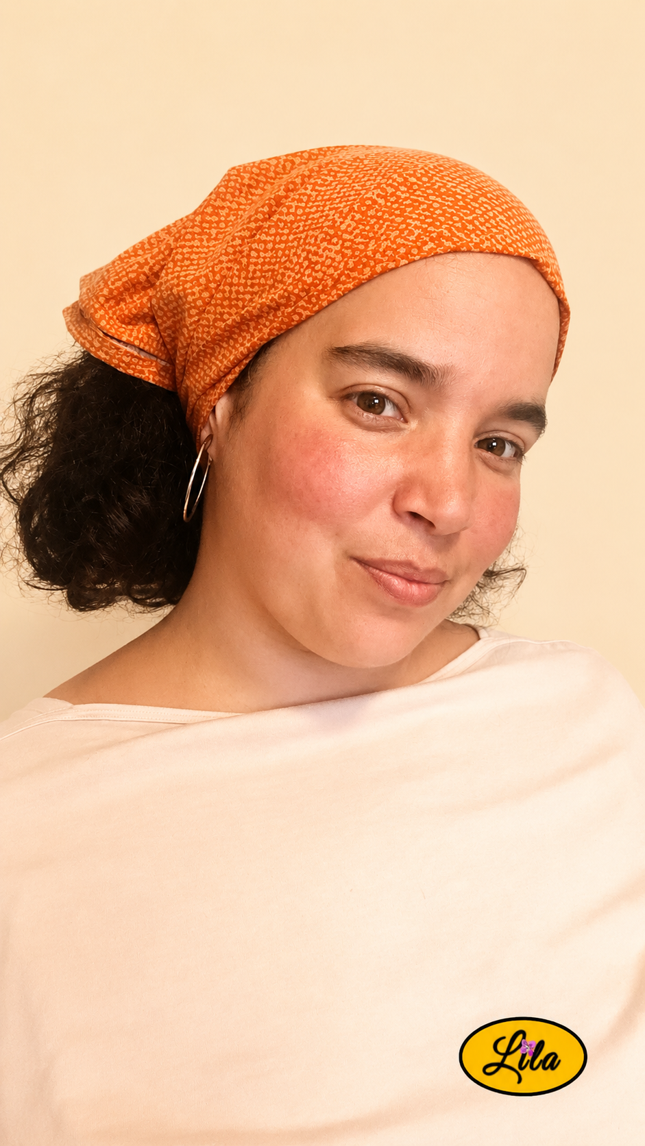 Bandana orange à motif texturé vintage porté dans les cheveux par une femme de profil droit avec les cheveux lâchés sous le bandana style chaleureux et artisanal