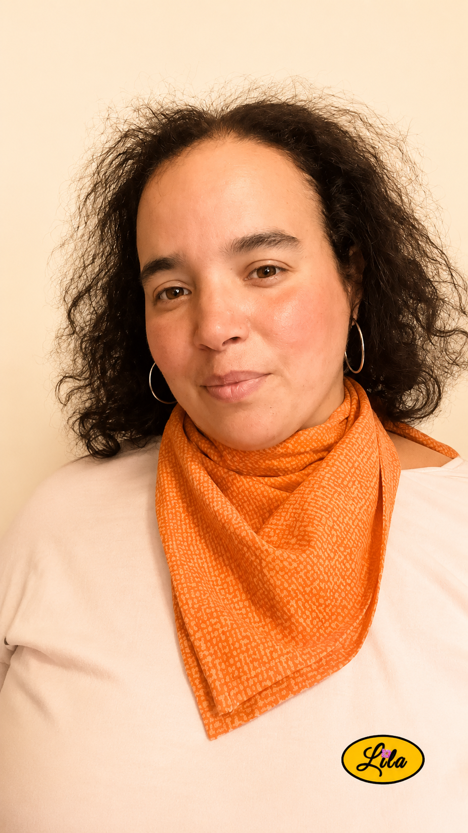 Bandana orange à motif texturé vintage porté autour du cou par une femme de face aux cheveux lâchés style rétro et accessoire de mode artisanal
