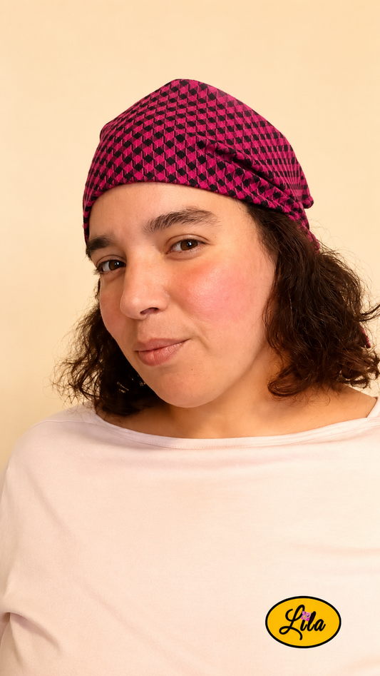 Bandana rose et noir à carreaux porté dans les cheveux par une femme de profil gauche avec les cheveux lâchés sous le bandana style tendance et rétro