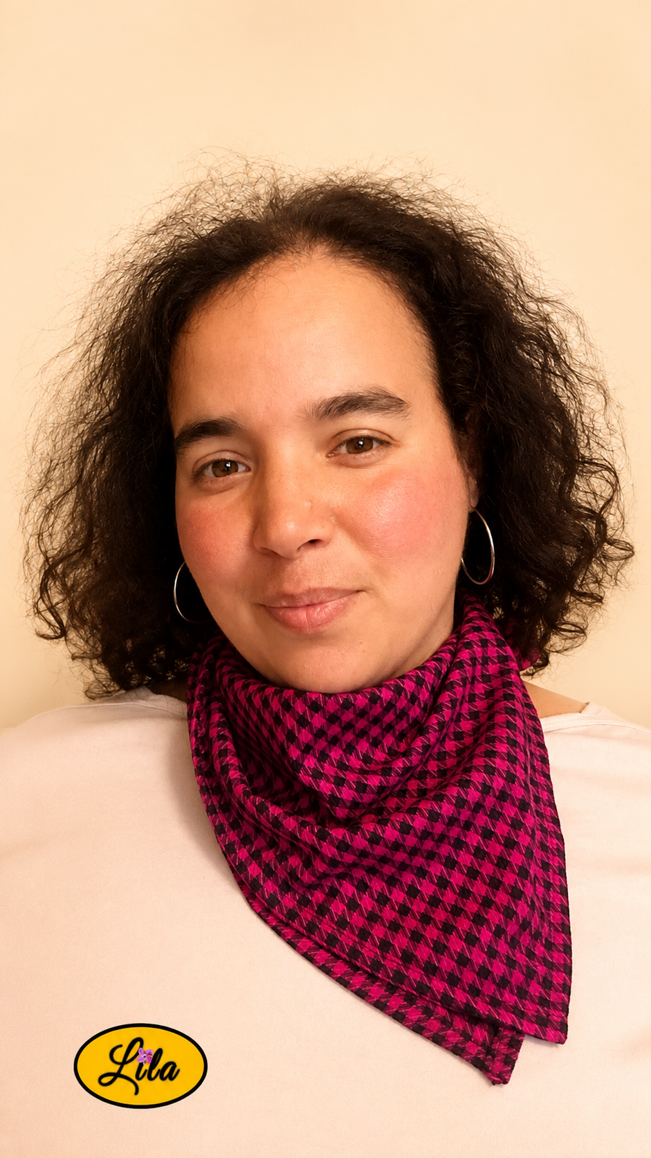 Bandana rose et noir à carreaux porté autour du cou par une femme de face aux cheveux lâchés style chic, rétro et accessoire de mode artisanal