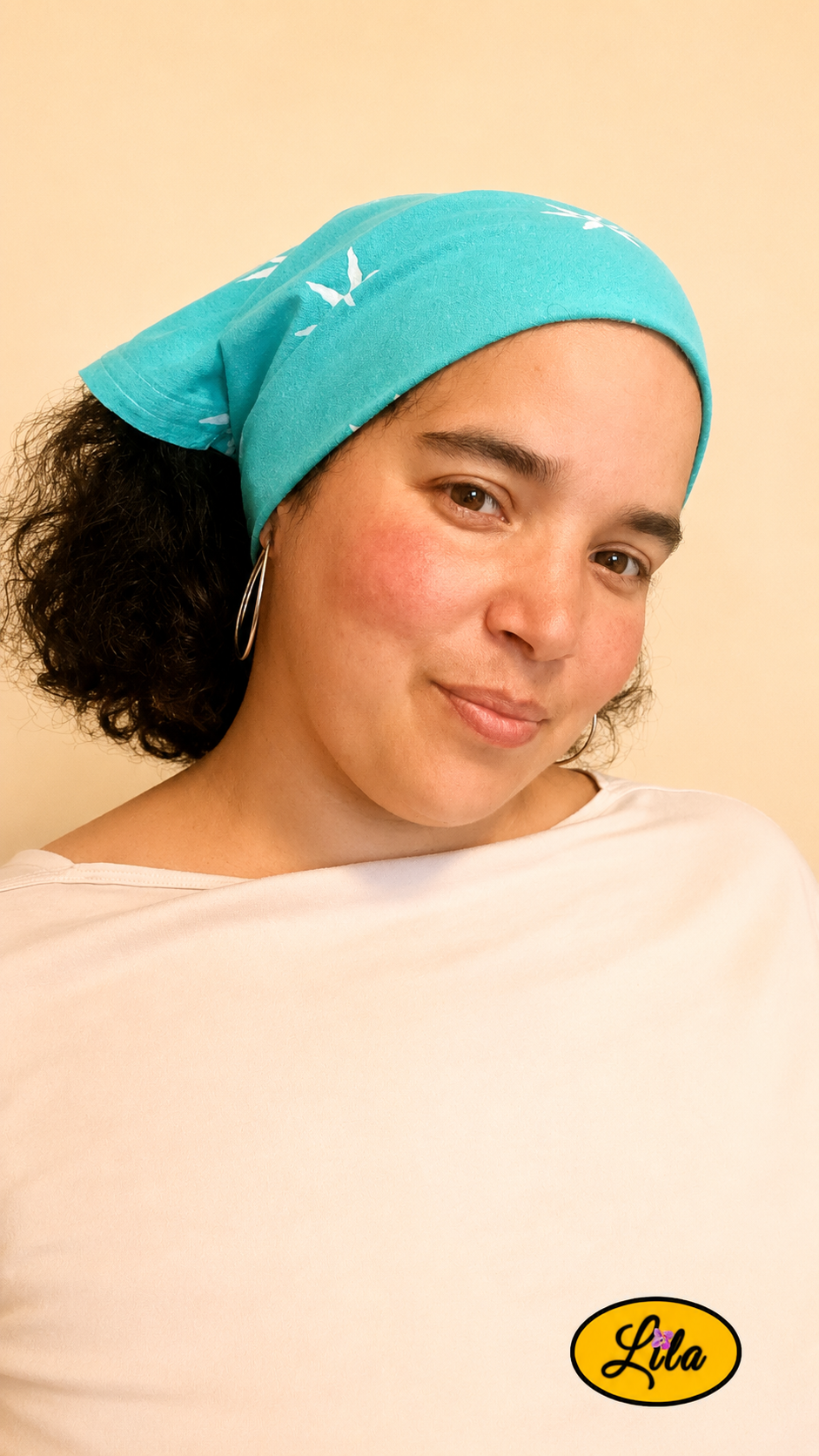 Bandana vert d'eau à motifs soleils porté dans les cheveux par une femme de profil droit avec les cheveux lâchés sous le bandana style naturel et tendance