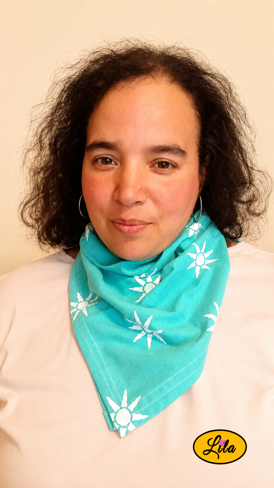Bandana vert d'eau à motifs soleils porté autour du cou par une femme de face aux cheveux lâchés style estival, bohème et accessoire de mode artisanal