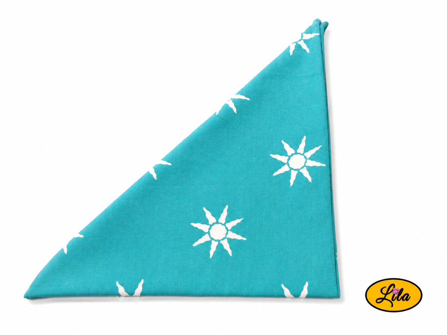 Bandana vert d'eau à motifs soleils plié en triangle vu de haut sur fond clair mettant en valeur les motifs et les finitions du tissu