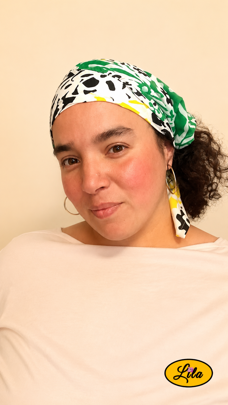 Bandana vert et jaune à motifs floraux vintage porté dans les cheveux par une femme de profil gauche avec les cheveux lâchés sous le bandana, côté vert visible, style bohème et vintage