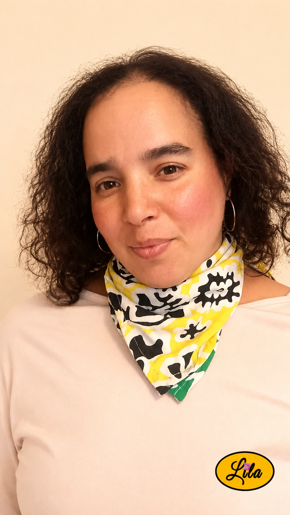 Bandana vert et jaune à motifs floraux vintage porté autour du cou par une femme de face aux cheveux lâchés avec la tête légèrement inclinée et un léger sourire, côté jaune visible, style bohème et romantique