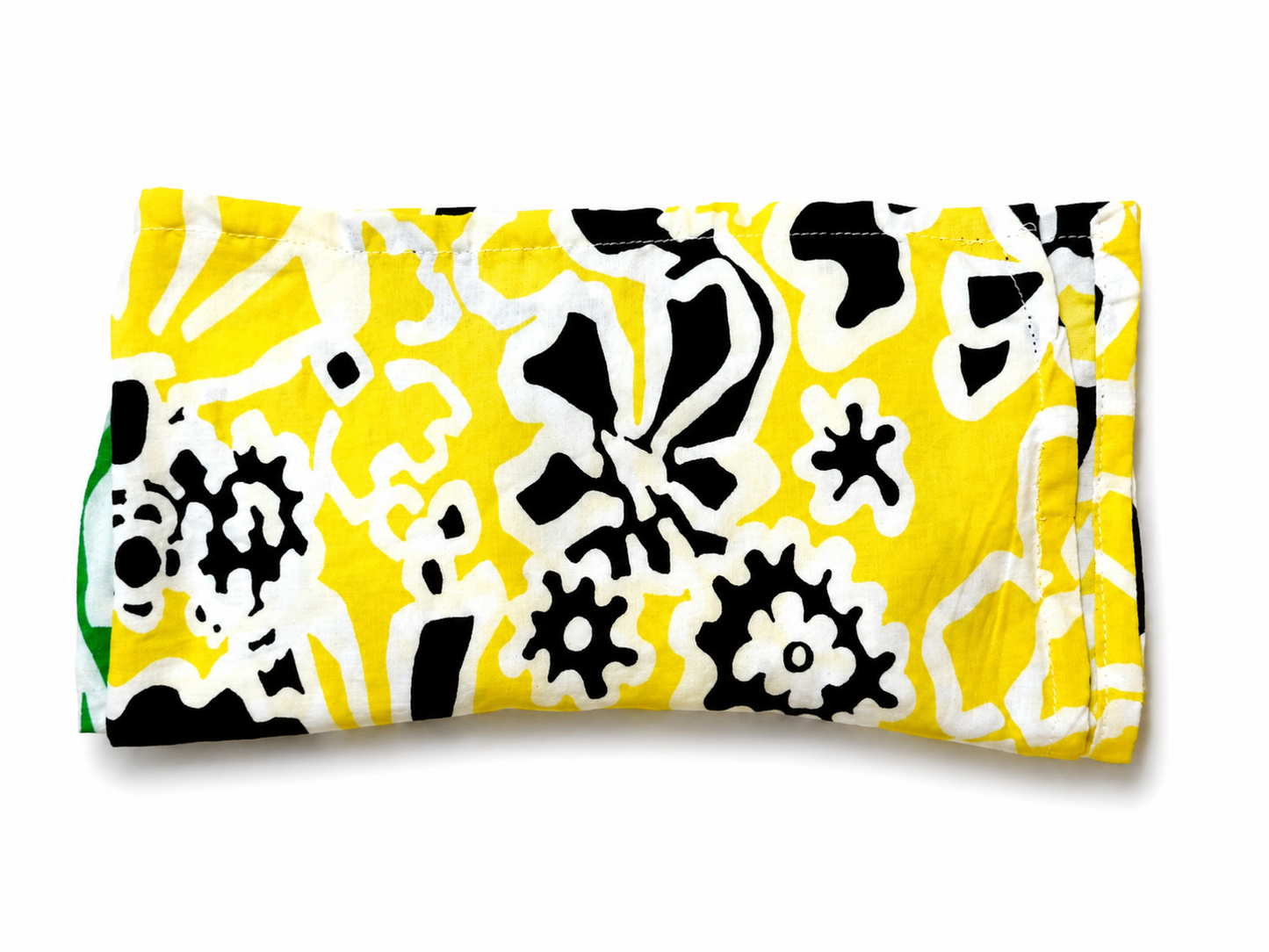Bandana vert et jaune à motifs floraux vintage plié en rectangle avec le côté jaune visible vu de haut sur fond clair style bohème et artisanal