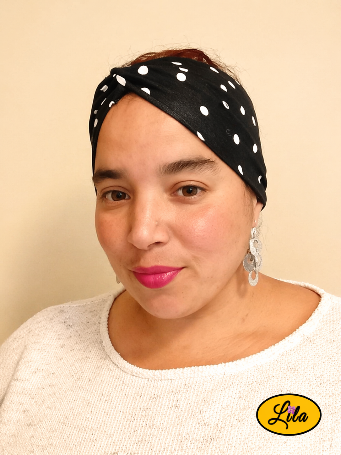 Bandeau en tissu noir à pois blancs porté de face avec noeud au-dessus de la tête