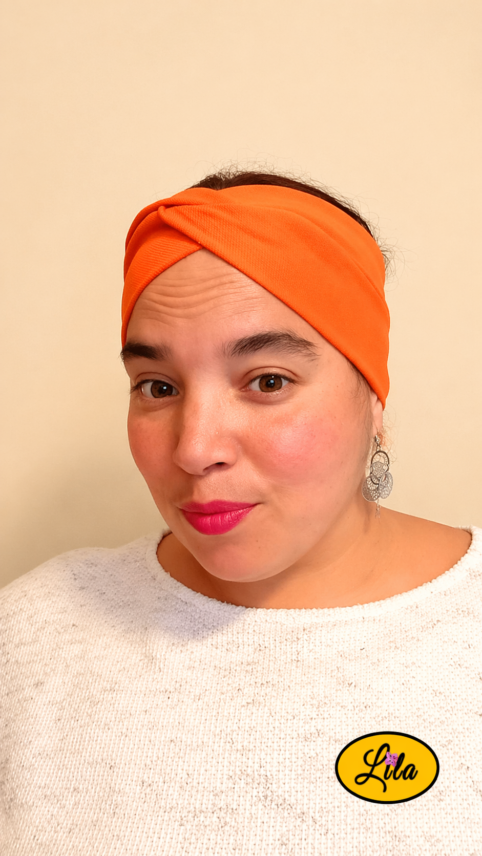 Bandeau en tissu orange porté de face tête légèrement inclinée vers la gauche avec noeud au-dessus