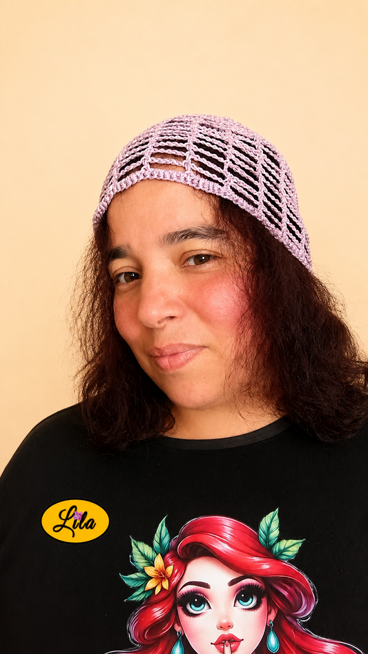 Bonnet d'été en crochet ajouré lilas porté par un mannequin légèrement de profil gauche avec les cheveux lâchés, mettant en valeur son motif ajouré, sa légèreté et sa confection artisanale