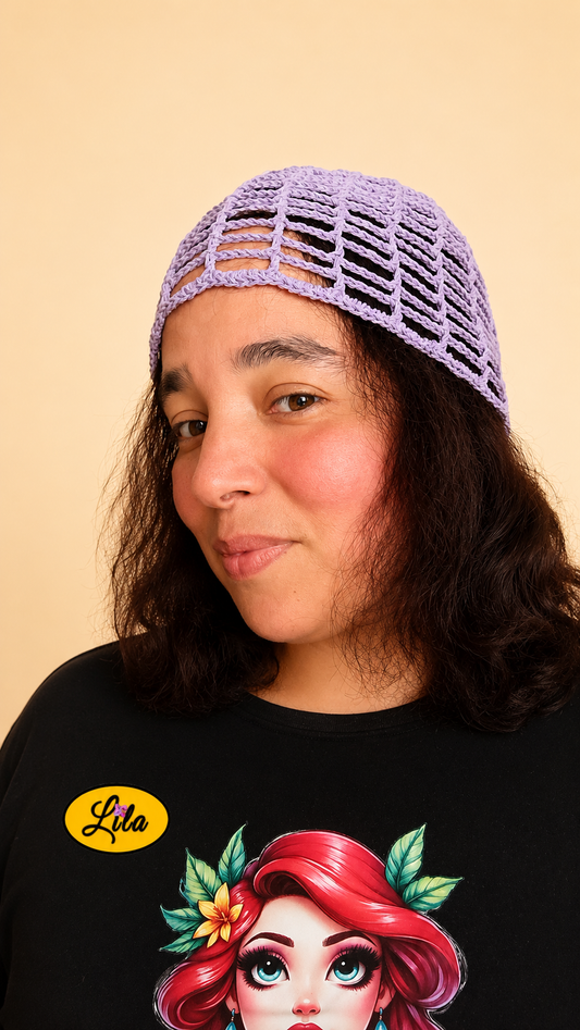 Bonnet d'été en crochet ajouré mauve porté par un mannequin légèrement de profil gauche mettant en valeur sa maille ajourée, sa coupe confortable et sa confection artisanale