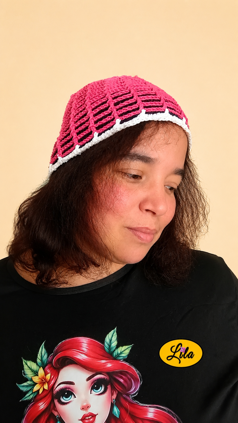 Bonnet d'été en crochet ajouré rose avec bande blanche porté par un mannequin de profil droit, tête légèrement penchée et regard vers le bas, mettant en valeur son style bohème, sa légèreté et sa réalisation artisanale