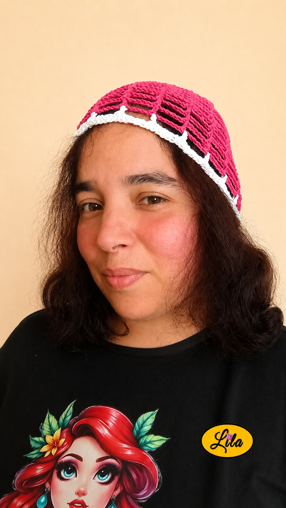 Bonnet d'été en crochet ajouré rose avec bande blanche porté par un mannequin de profil gauche avec les cheveux lâchés mettant en valeur sa maille ajourée, son contraste de couleurs et sa confection artisanale