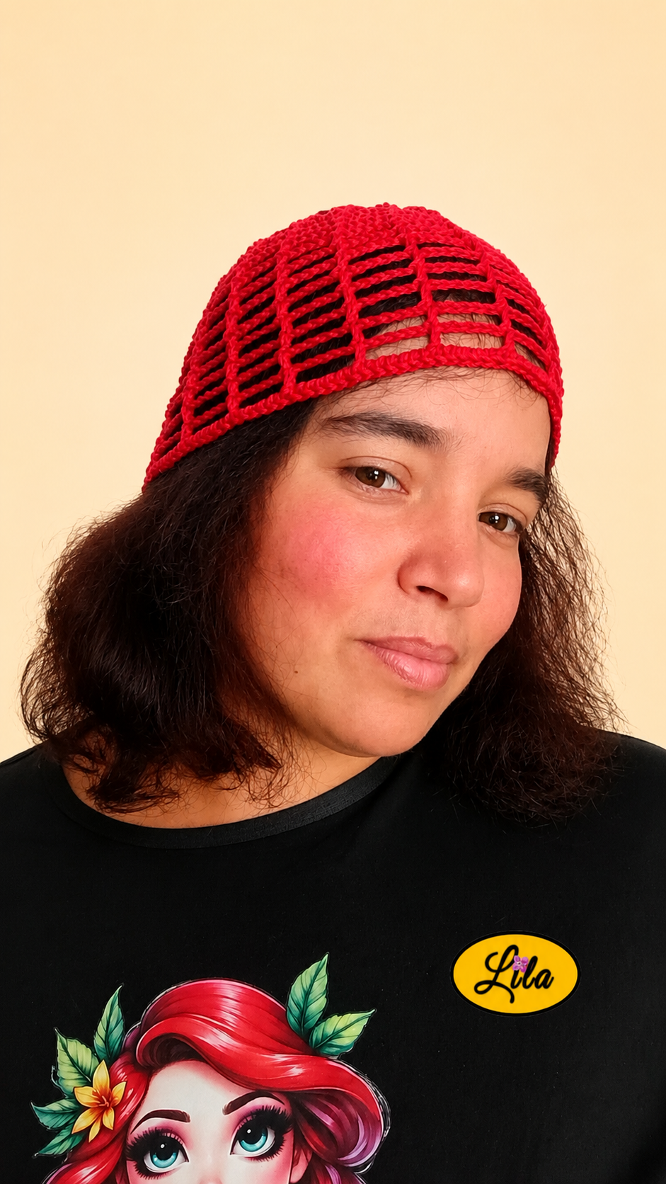 Bonnet d'été en crochet ajouré rouge porté par un mannequin de profil droit avec la tête légèrement inclinée et le visage davantage de face mettant en valeur son style bohème, sa légèreté et son crochet fait main
