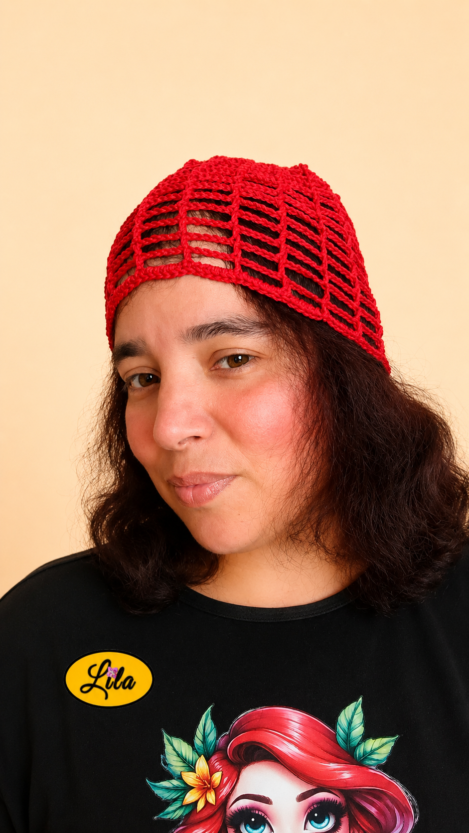 Bonnet d'été en crochet ajouré rouge porté par un mannequin de profil gauche avec les cheveux lâchés et le regard dirigé vers l'avant mettant en valeur son tombé naturel, sa maille ajourée et sa réalisation artisanale