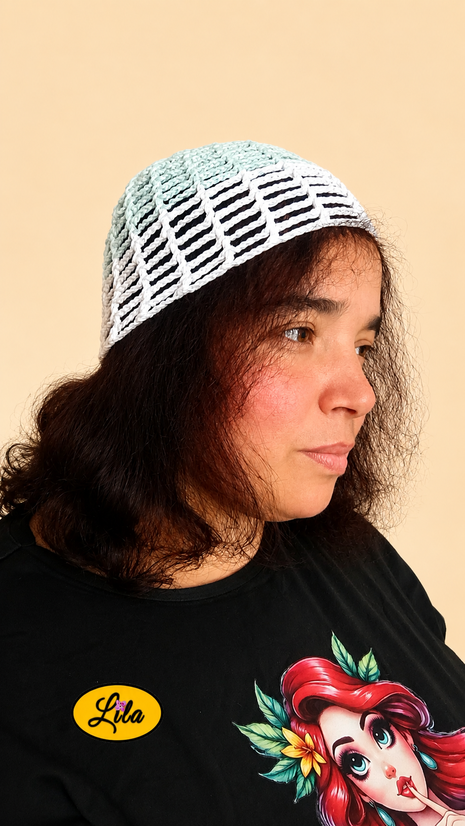 Bonnet d'été en crochet ajouré vert menthe avec bande blanche porté par un mannequin de profil droit avec les cheveux lâchés et le regard tourné vers la droite mettant en valeur son style bohème, sa légèreté et son crochet fait main