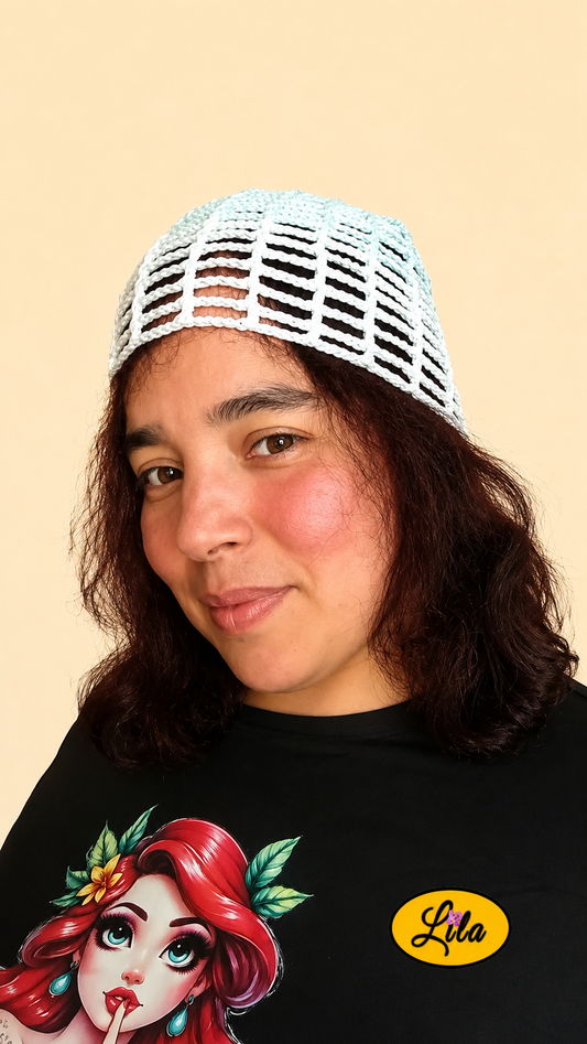 Bonnet d'été en crochet ajouré vert menthe avec bande blanche porté par un mannequin de profil gauche avec les cheveux lâchés et le regard dirigé vers l'avant mettant en valeur son contraste de couleurs, sa maille ajourée et sa confection artisanale