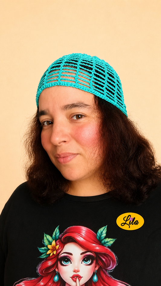 Bonnet d'été en crochet ajouré vert turquoise porté par un mannequin de profil gauche avec les cheveux lâchés et le regard de face mettant en valeur sa maille ajourée, sa couleur lumineuse et sa confection artisanale
