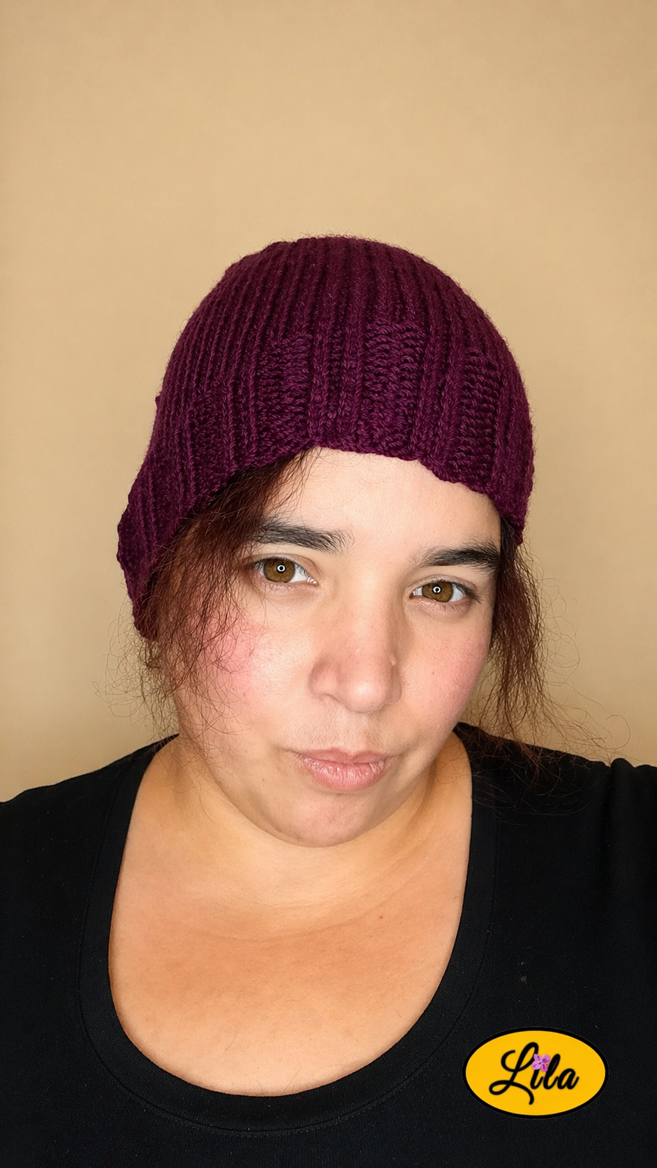 Bonnet en laine prune porté de face avec mèches de cheveux sur le visage style élégant