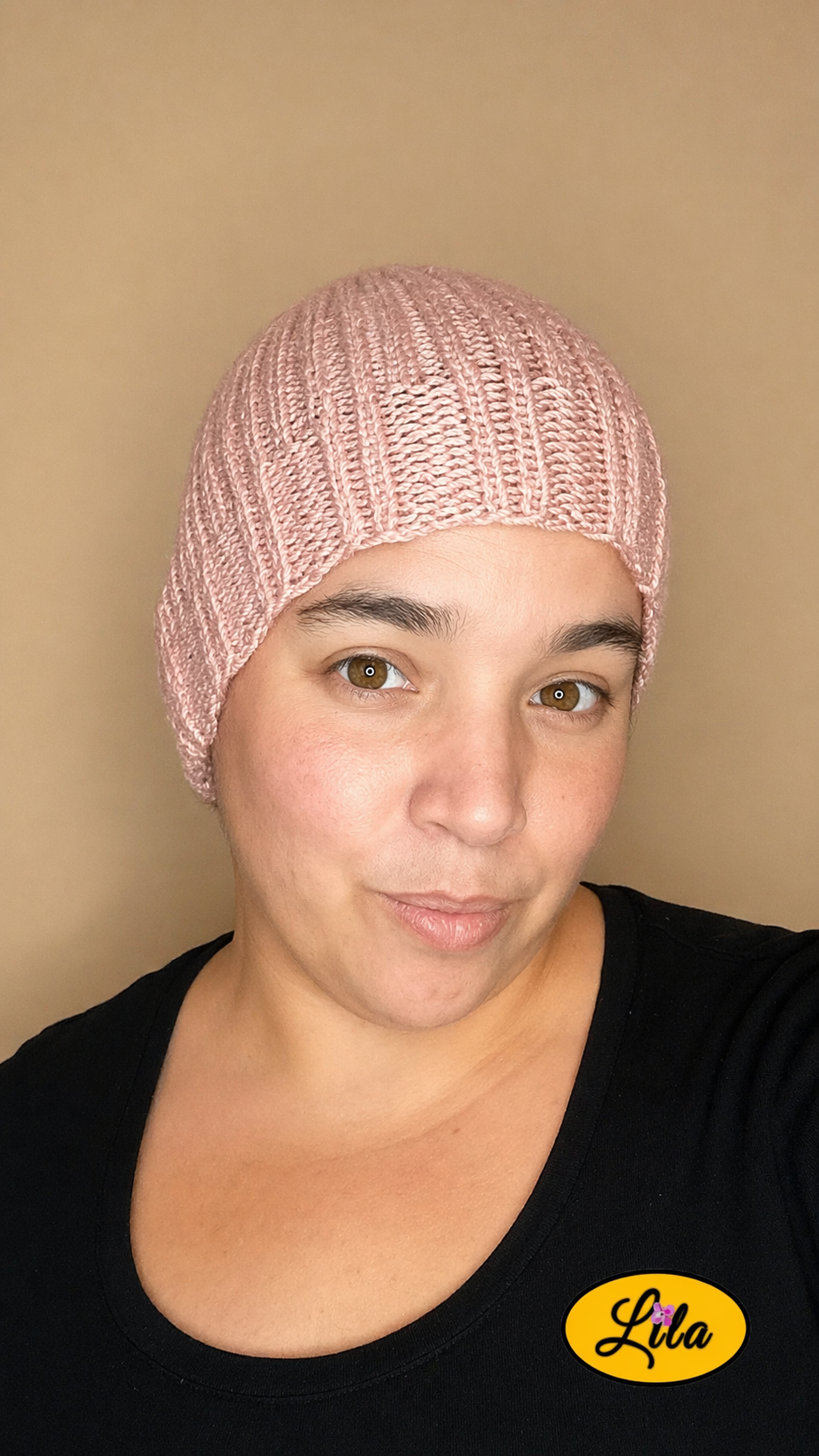 Bonnet en laine vieux rose porté par une femme vue de face style doux et tendance