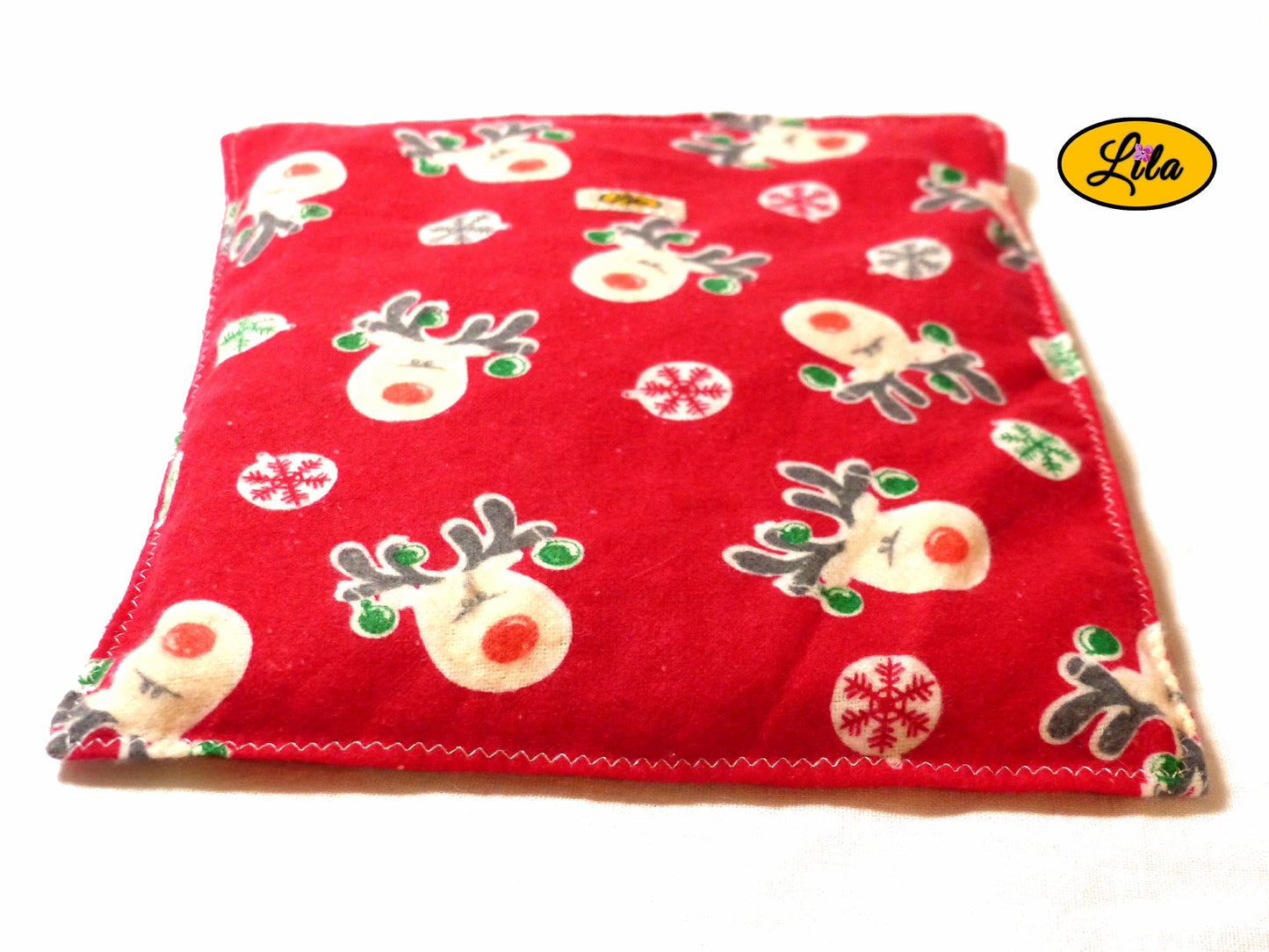 Bouillotte motif rennes sur fond rouge réalisée dans un ancien pyjama recyclé remplie de noyaux de cerise vue de face sur fond blanc style cocooning et chaleureux