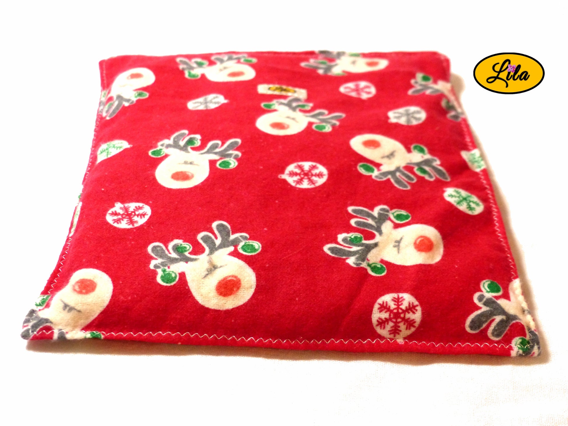 Bouillotte motif rennes sur fond rouge réalisée dans un ancien pyjama recyclé remplie de noyaux de cerise vue de face sur fond blanc style cocooning et chaleureux