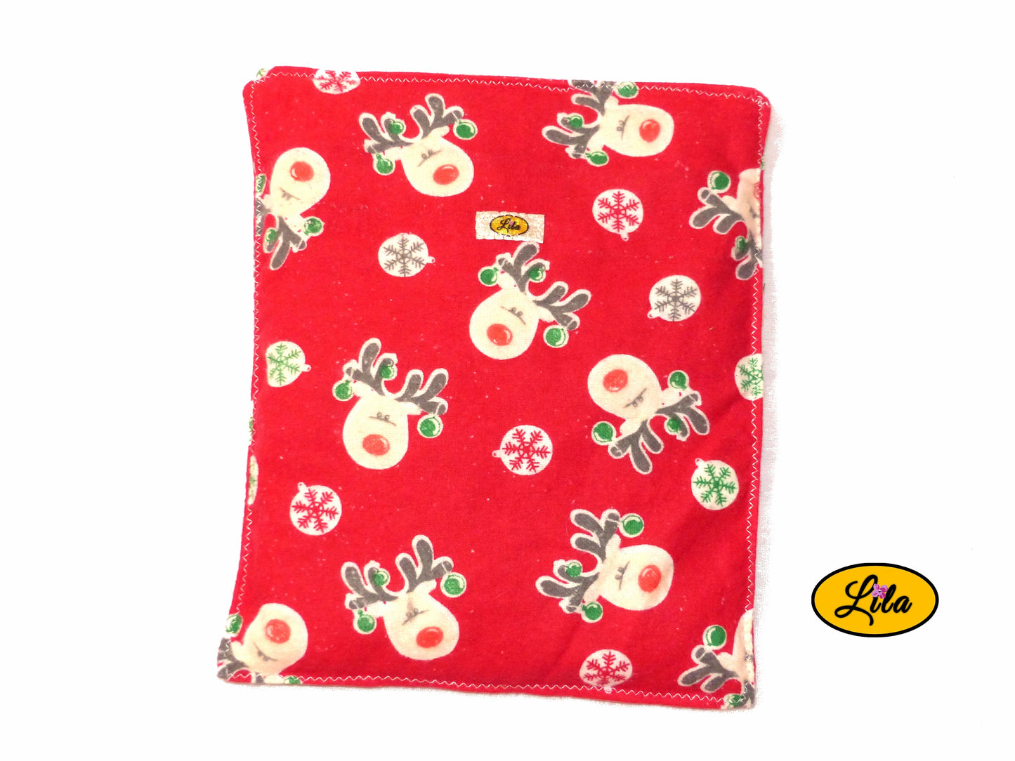 Bouillotte motif rennes sur fond rouge réalisée dans un ancien pyjama recyclé remplie de noyaux de cerise vue de haut sur fond blanc style hivernal et artisanal