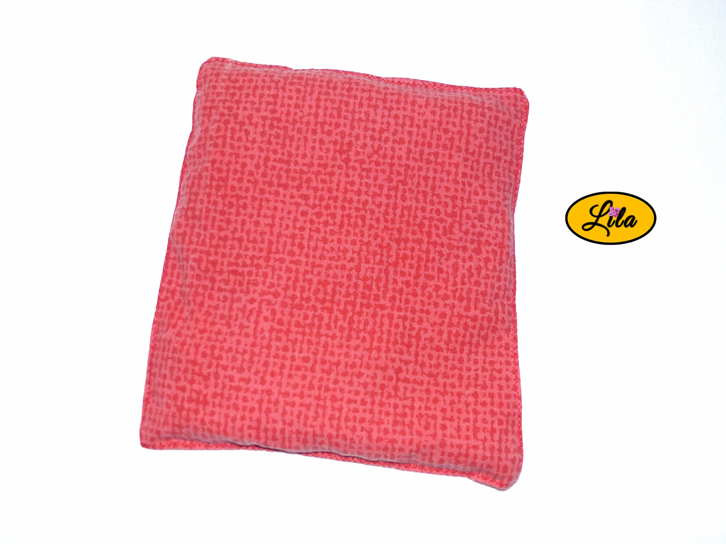 Bouillotte simple rouge et orange réalisée dans d’anciens draps de lit recyclés remplie de noyaux de cerise vue de dos sur fond blanc style artisanal et chaleureux